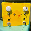 Yellow guitar effects pedal with duck graphic, two white knobs, two toggle switches, and two footswitches.