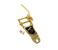 Gold-colored Bigsby vibrato tailpiece with lever and four screws on a white background.