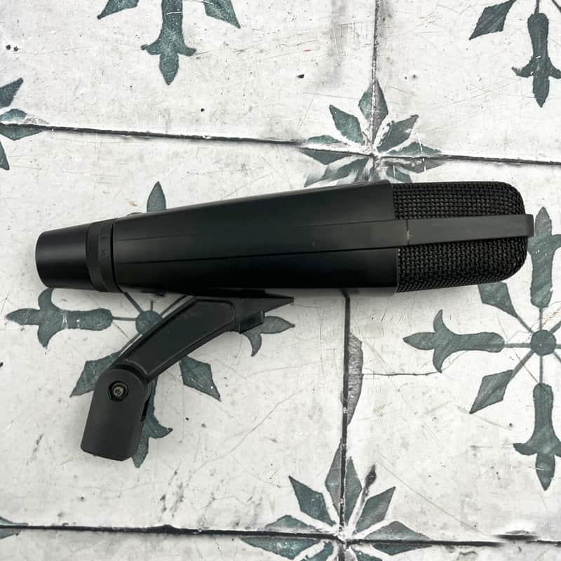 A Sennheiser MD 421 II cardioid dynamic microphone shown at an angle, with its large slotted grille head, tapering ribbed body, five-position bass roll-off switch near the base, and 3-pin XLR output connector.