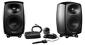 Two black studio monitor speakers with Genelec branding and calibration microphone with accessories on white background.