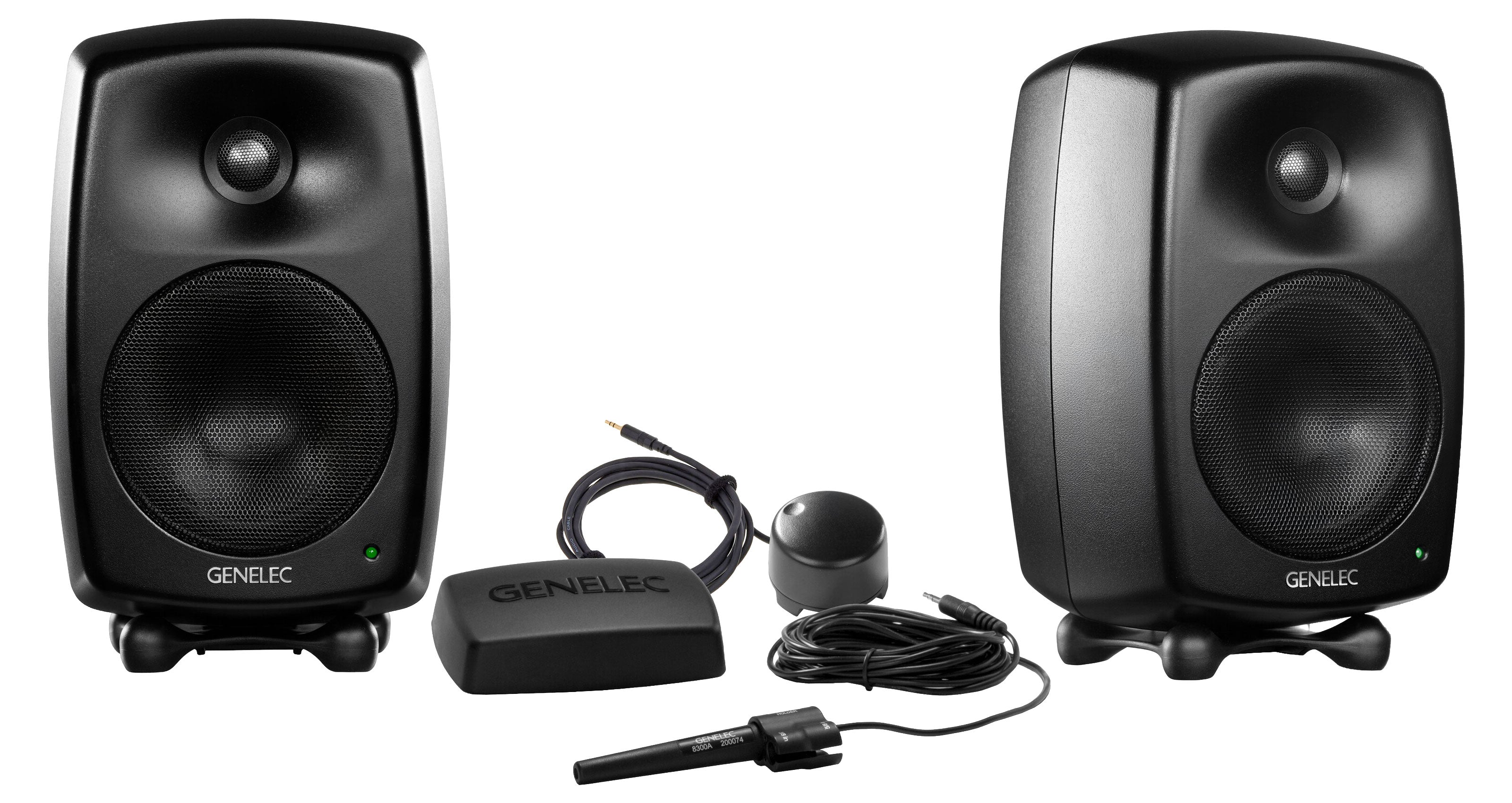 Two black studio monitor speakers with Genelec branding and calibration microphone with accessories on white background.