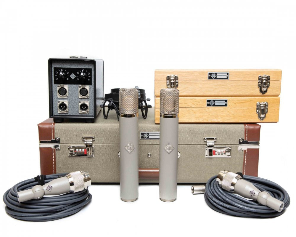 Two large microphones, cables, a shock mount, two wooden cases, a carrying case, and a control box with XLR connectors and knobs.