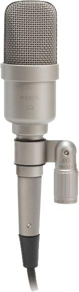 Silver studio microphone with metal mesh grille and attached cable shown from front view