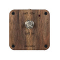 Wooden square device with a central metal push button switch and red indicator light above it.