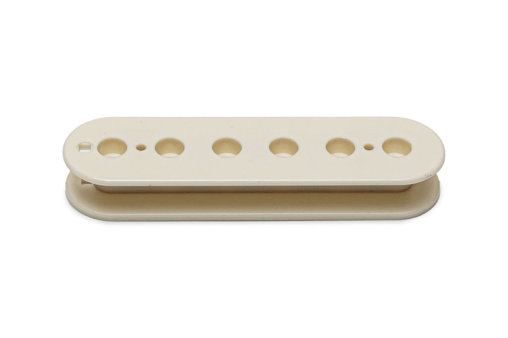 Vintage white plastic bobbin for a guitar pickup with six holes along its length.
