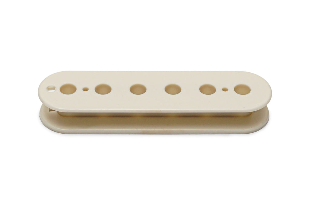 A vintage white plastic pickup bobbin with six holes in a row, photographed on a white background.
