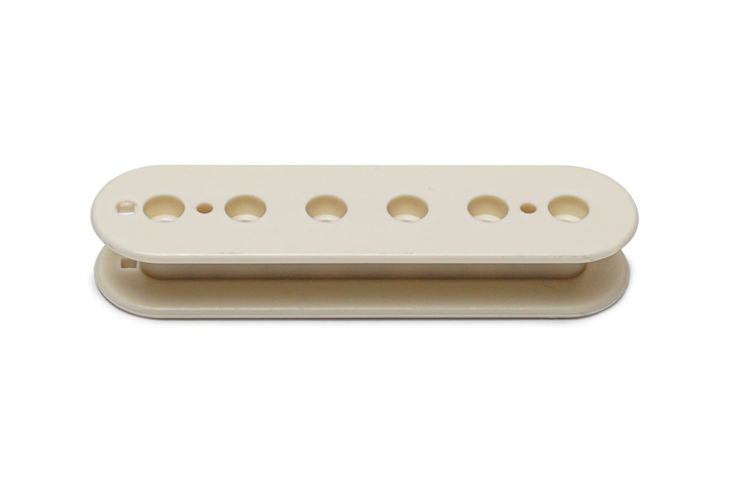 Vintage white plastic pickup bobbin shell with six holes and two small round holes on a white background.