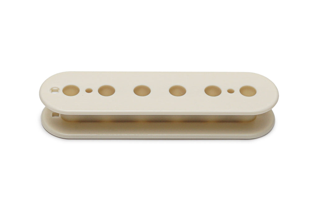 Vintage white plastic pickup bobbin with multiple holes for strings, shown from a side angle on white background.