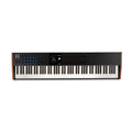Black keyboard controller with 88 keys, blue-lit pads, multiple knobs and faders, and a small display screen.