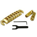 Gold wraparound guitar bridge with two knurled posts, an Allen wrench, and a black adjustment wrench on a white background.