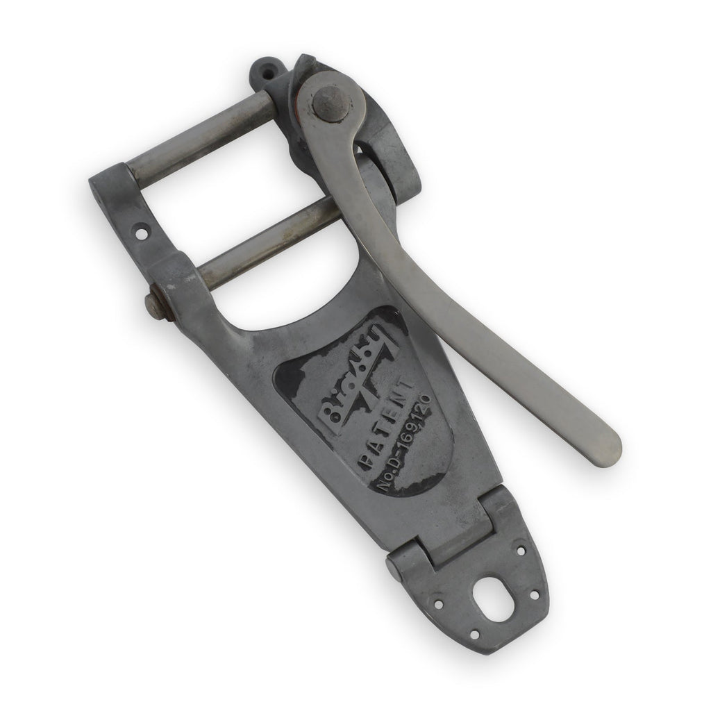 Metal vibrato unit with lever arm and patent information embossed on its surface.