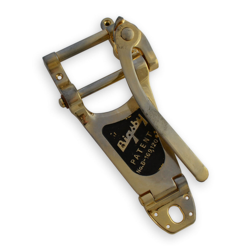 Gold-colored vibrato tailpiece with a lever and Bigsby patent label attached.