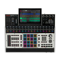 Top-down view of a music production controller with multiple pads, knobs, buttons, and a large color display showing a digital audio workstation interface.