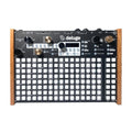 Top view of a black synthesizer with wooden side panels, many white buttons, knobs, and a small screen.
