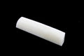 A white curved elongated bone nut or saddle piece shown on a black background.