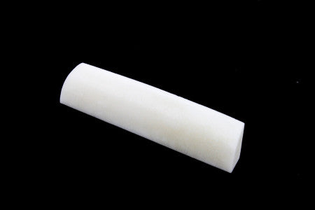 A white curved elongated bone nut or saddle piece shown on a black background.