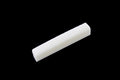 White slotted bone nut for acoustic guitar on a black background.