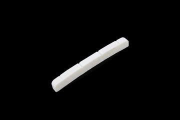 A white slotted bone nut with six string slots for a precision bass style instrument.