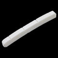 White slotted nut piece for a stringed instrument on a black background.