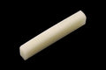 Off-white bone nut with multiple vertical slots on a black background.
