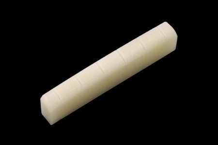 Off-white bone nut with multiple vertical slots on a black background.