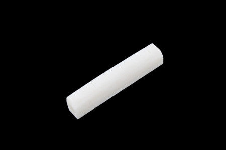 White slotted bone nut for guitar, shown on black background.