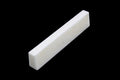 A white rectangular slant-cut bone nut or saddle piece for a stringed instrument.