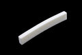 Curved off-white bone guitar nut on black background.