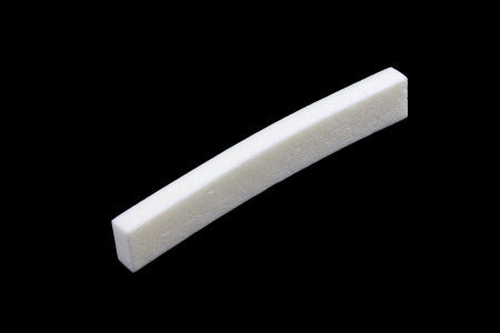Curved off-white bone guitar nut on black background.