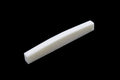 White rectangular bone nut or saddle piece on a black background.
