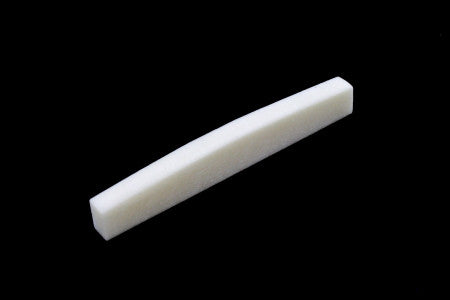 White rectangular bone nut or saddle piece on a black background.