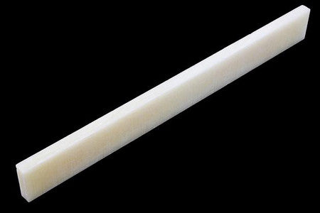 Off-white rectangular blank slab likely used as a bone saddle for stringed instruments.