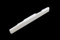 White elongated guitar saddle with multiple compensation notches on a black background.