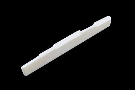 White elongated guitar saddle with multiple compensation notches on a black background.