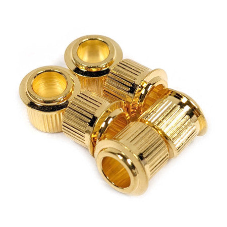 Five gold-colored metal bushings with ribbed sides and hollow centers.