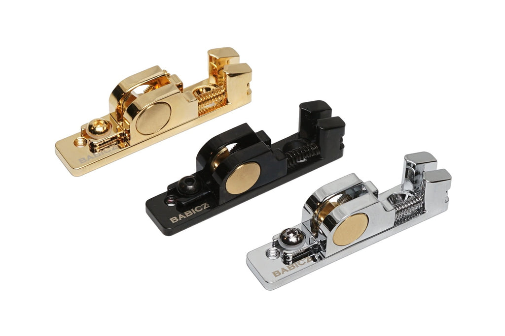 Three individual guitar saddles in gold, black, and silver finishes with adjustment screws.