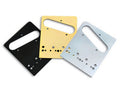 Three rectangular metal shim plates with multiple holes in black, gold, and silver colors are arranged overlapping on a white background.