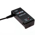 Black rectangular power supply with CIOKS CRUX branding, a barrel power connector, 1/4 inch output jack, and voltage switch.