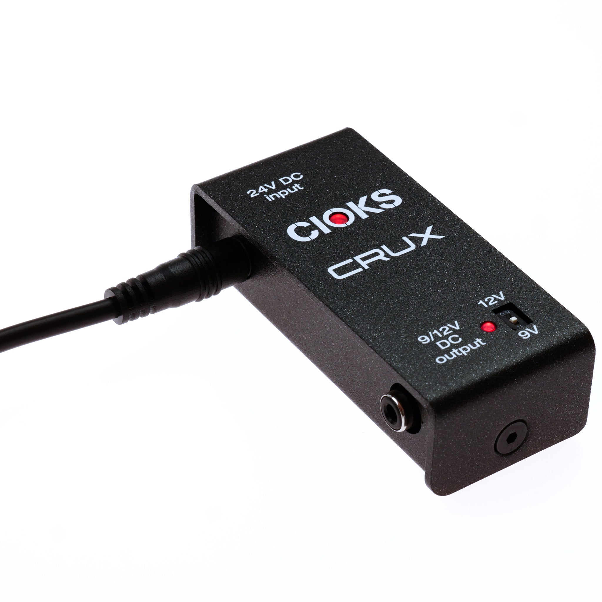 Black rectangular power supply with CIOKS CRUX branding, a barrel power connector, 1/4 inch output jack, and voltage switch.