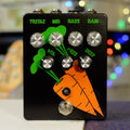 Black guitar pedal with green and orange carrot graphics and seven control knobs labeled with audio settings.