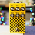 Yellow guitar effects pedal with six knobs, a footswitch, and black checkerboard pattern.