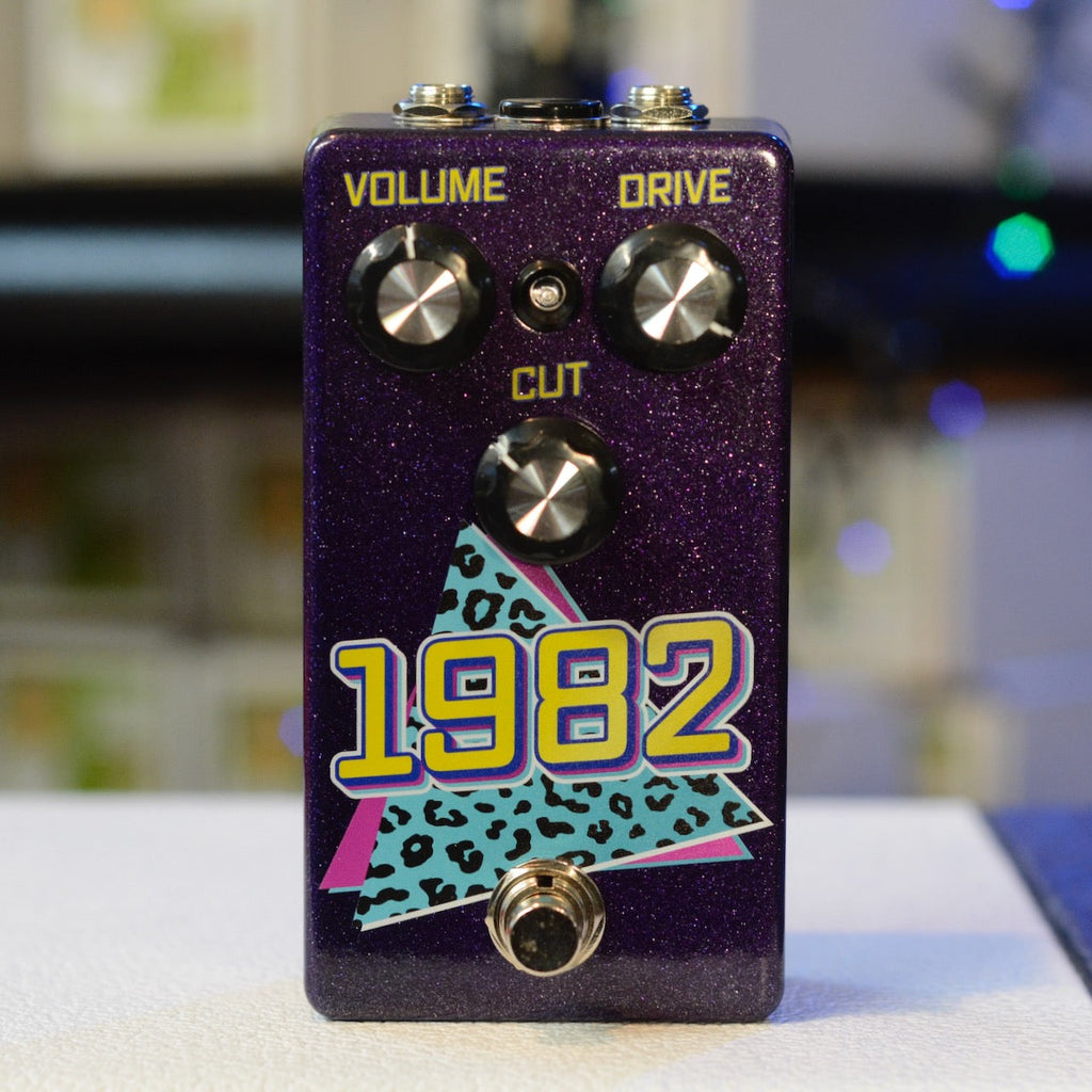 Purple guitar effects pedal with three control knobs labeled Volume, Drive, and Cut, and a footswitch below.