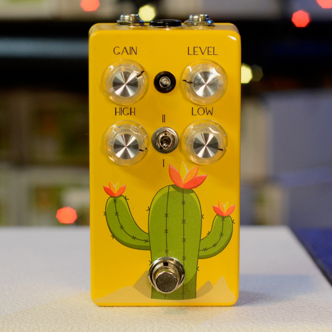 Yellow guitar effects pedal with cactus illustration, four knobs, toggle switch, and footswitch