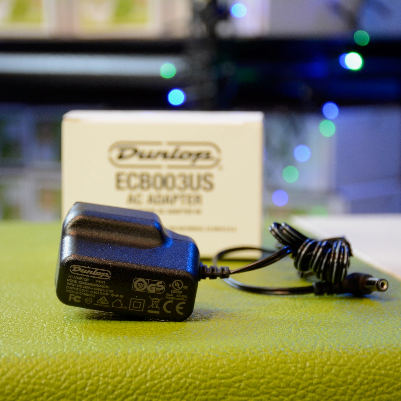 Black Dunlop AC adapter with power cable and white Dunlop EC8003US box on green surface