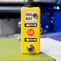 Yellow rectangular guitar pedal with footswitch, three 1/4 inch jacks and directional labels on the front.