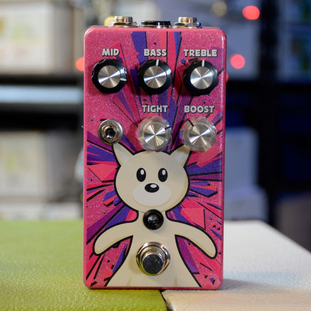 Pink guitar effects pedal with cartoon dog graphic and knobs labeled Mid, Bass, Treble, Tight, and Boost.