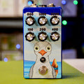 Blue guitar pedal with six rotary knobs labeled with frequency numbers and a foot switch, featuring a cartoon bird graphic.