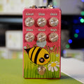 Pink guitar effects pedal with six control knobs, a footswitch, and bee and flower graphics on front panel.