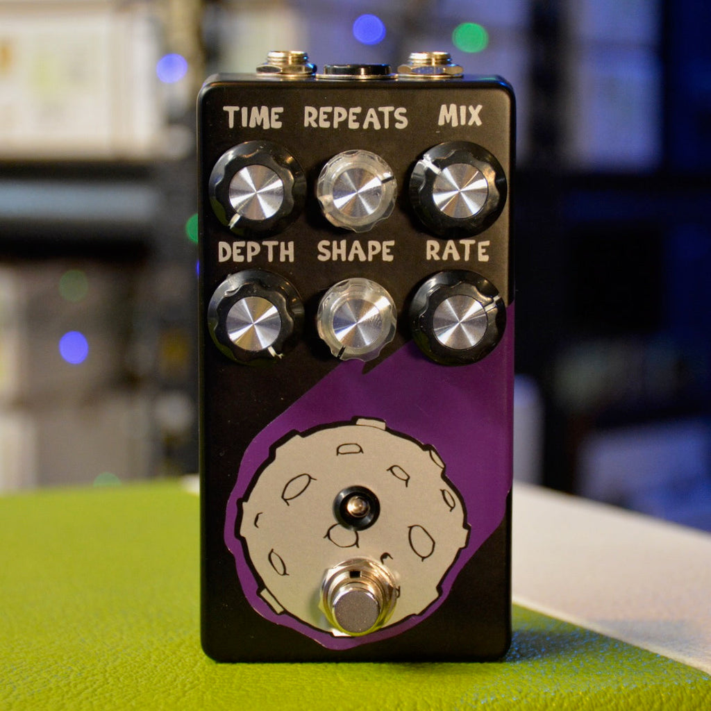 Black and purple guitar effects pedal with six control knobs, a toggle switch, and a footswitch on the front panel