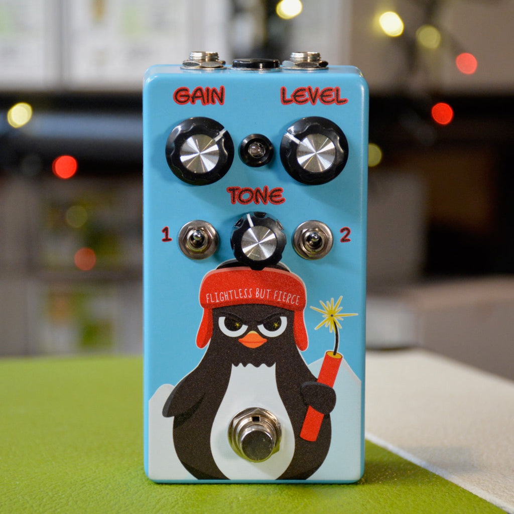 Blue guitar effects pedal with a penguin graphic and three knobs labeled Gain, Level, and Tone.